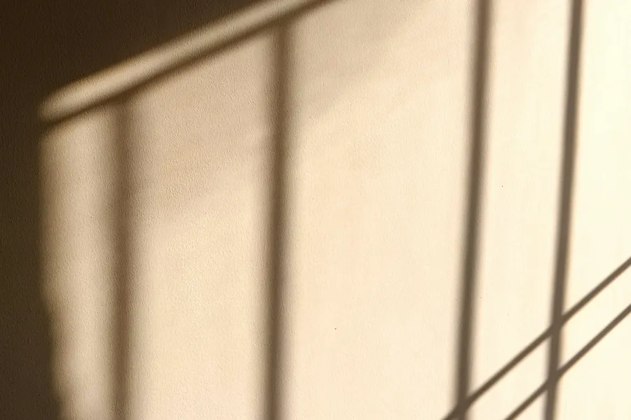 Sombra de una ventana proyectada sobre una pared cálida.
